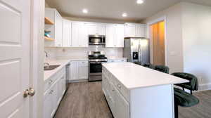 Kitchen with appliances with stainless steel finishes, a kitchen bar, decorative backsplash, dark wood finished floors, and a center island