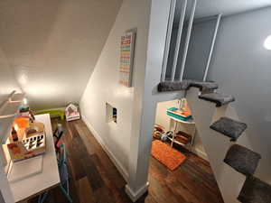 Stairs featuring a textured ceiling and hardwood / wood-style flooring