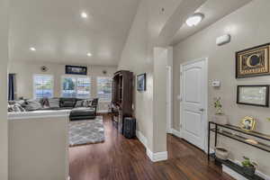 Living room featuring vaulted ceiling, dark wood-style floors, arched walkways, and recessed lighting