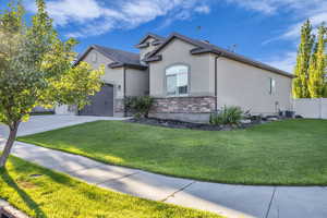 View of front of house with stucco siding, an attached garage, stone siding, and concrete driveway