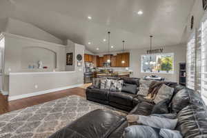 Living room with vaulted ceiling, wood finished floors, recessed lighting, and a chandelier