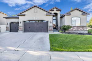 View of front facade with stone siding, a garage, and stucco siding
