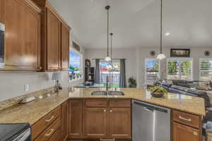 Kitchen featuring stainless steel appliances, plenty of natural light, a peninsula, open floor plan, and lofted ceiling