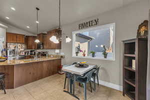 Kitchen featuring lofted ceiling, stainless steel appliances, light stone counters, recessed lighting, and pendant lighting