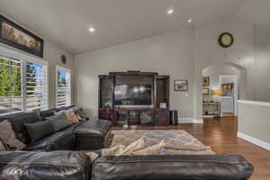 Living area featuring arched walkways, wood finished floors, recessed lighting, washer / clothes dryer, and high vaulted ceiling