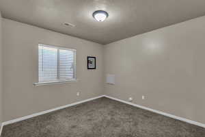 Carpeted empty room featuring baseboards and a textured ceiling
