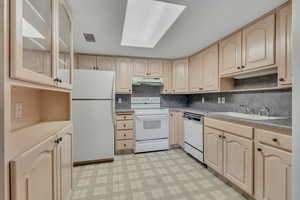 Kitchen featuring light floors, white appliances, light brown cabinets, decorative backsplash, and under cabinet range hood