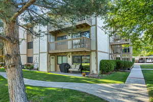 End unit. Back of property with stucco siding, a balcony, and a yard