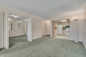Living room featuring light carpet and ornamental molding with view of kitchen