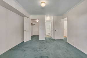 Master bedroom featuring carpet, crown molding, a walk in closet, and connected bathroom
