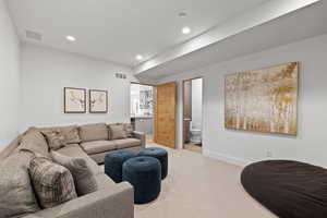 Living area with light colored carpet and recessed lighting