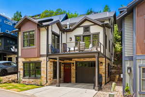 Craftsman inspired home featuring a balcony, stone siding, driveway, and a garage