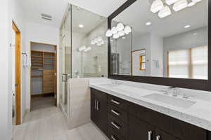 Full bath featuring double vanity, a shower stall, a spacious closet, and recessed lighting