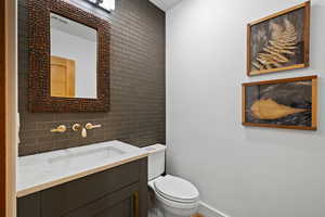 Half bathroom with vanity, tile walls, and backsplash