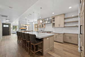 Kitchen with recessed lighting, light countertops, light wood-type flooring, a breakfast bar, and an island with sink