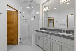 Bathroom featuring double vanity, a stall shower, tile patterned flooring, and recessed lighting