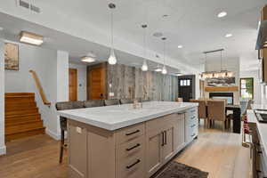Kitchen with open floor plan, light wood-style flooring, stove, decorative light fixtures, and recessed lighting