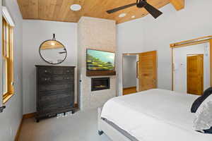 Bedroom with wooden ceiling, a large fireplace, carpet, and a towering ceiling