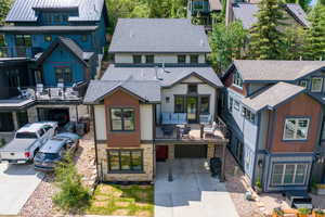 View of front of property featuring stone siding, concrete driveway, a balcony, a residential view, and a shingled roof