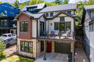 View of front of property with a balcony, stone siding, driveway, a garage, and a shingled roof