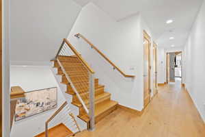 Staircase with wood finished floors and recessed lighting