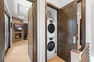 Washroom with stacked washer / dryer, light carpet, recessed lighting, and a fireplace