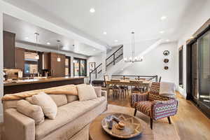 Living room with light wood finished floors, recessed lighting, stairway, and a chandelier