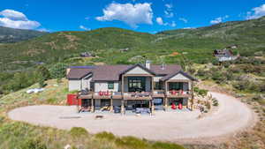 Back of house featuring a chimney, a patio area, a deck with mountain view, a shingled roof, and an outdoor living space with a fire pit