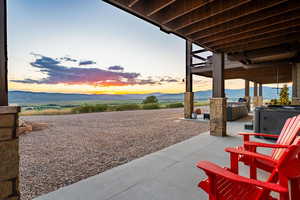 Patio terrace at dusk with a patio area, a mountain view, and a hot tub