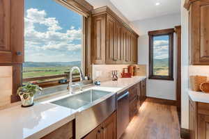 Kitchen featuring light wood-style floors, stainless steel dishwasher, and brown cabinets