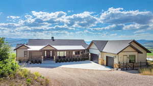 View of front of property featuring stone siding, a mountain view, driveway, and a shingled roof