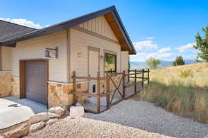 View of home's exterior featuring stone siding, roof with shingles, an attached garage, and driveway