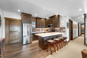 Kitchen with appliances with stainless steel finishes, dark brown cabinets, light countertops, tasteful backsplash, and a peninsula