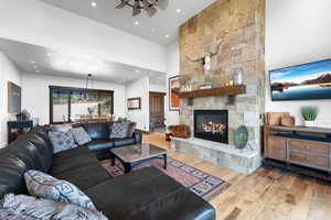 Living room featuring wood finished floors, a fireplace, a ceiling fan, recessed lighting, and a high ceiling