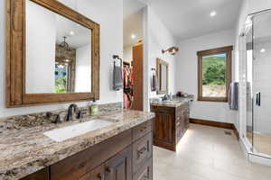 Bathroom with two vanities, a shower stall, tile patterned flooring, recessed lighting, and a walk in closet