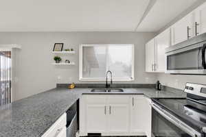 Kitchen with stainless steel appliances, white cabinets, and open shelves