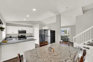 Kitchen featuring white cabinetry, stainless steel appliances, a peninsula, lofted ceiling, and recessed lighting