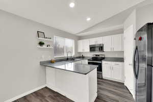 Kitchen with appliances with stainless steel finishes, vaulted ceiling, open shelves, a peninsula, and recessed lighting