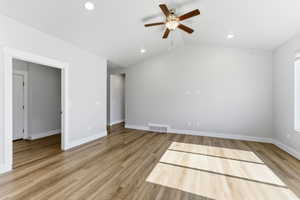 Spare room with light wood-type flooring, a ceiling fan, vaulted ceiling, and recessed lighting