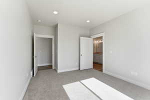 Unfurnished bedroom featuring light colored carpet, connected bathroom, and recessed lighting