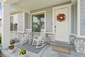View of exterior entry featuring stone siding and covered porch