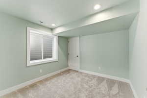 Carpeted spare room with baseboards and recessed lighting
