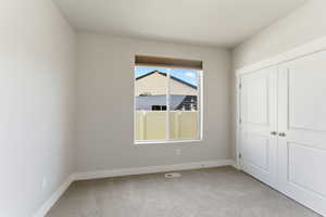 Unfurnished bedroom with light carpet and a closet