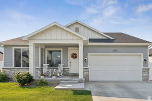 View of front of property with stone siding, a porch, a shingled roof, and board and batten siding