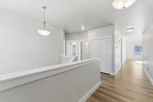 Hall with an upstairs landing, light wood-type flooring, and recessed lighting