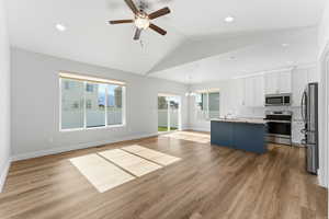 Unfurnished living room featuring a chandelier, lofted ceiling, ceiling fan, dark wood finished floors, and recessed lighting