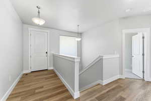 Corridor featuring an upstairs landing and light wood-type flooring
