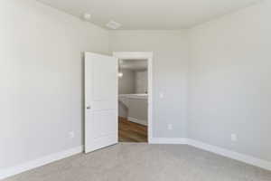 Empty room with light colored carpet and baseboards