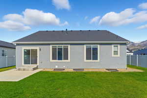 Rear view of house with a fenced backyard, stucco siding, roof with shingles, and a patio area