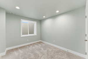 Empty room with carpet floors, recessed lighting, and a textured ceiling